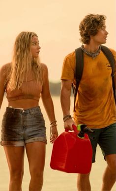 a man and woman standing next to each other with a red jug in their hand