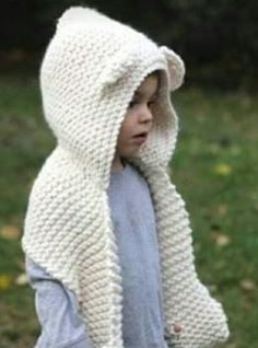 a little boy wearing a white knitted hooded jacket