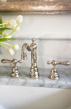 a bathroom sink with two faucets and flowers