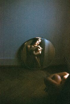 a woman is laying down in a round object on the floor next to a blue wall