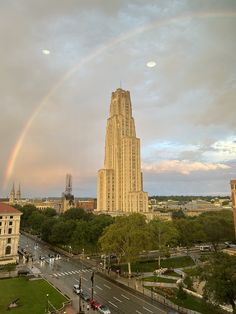 a rainbow in the sky over a city with tall buildings and cars on the street