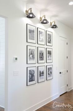 a white room with pictures hanging on the wall and lights above it that are black and white