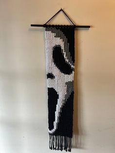 a wall hanging made out of beads with a black and white design on it's side