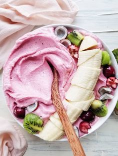 a bowl filled with fruit and yogurt next to sliced kiwis