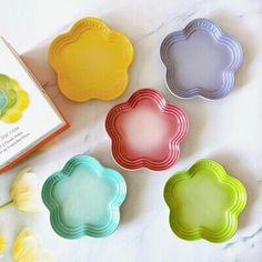 four cookie tins sitting on top of a table next to a book and flowers