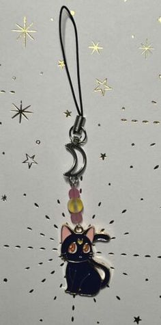 a keychain with a black cat on it's face and stars in the background