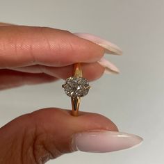 a woman's hand holding an engagement ring with a diamond on the top and bottom