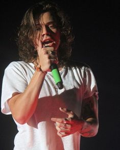 a man holding a microphone in his right hand and wearing a white t - shirt