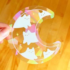 a person holding up a clear sticker with cats on the moon and stars around it