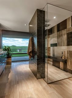 a modern bathroom with wood flooring and large glass shower area, overlooking the landscape