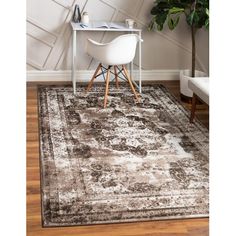 an area rug with a chair and desk in front of a white wall, next to a potted plant