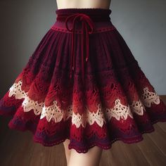 a woman wearing a red and white crochet skirt with an attached waist tie