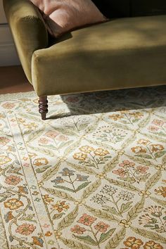 a green couch sitting on top of a wooden floor next to a white and orange rug