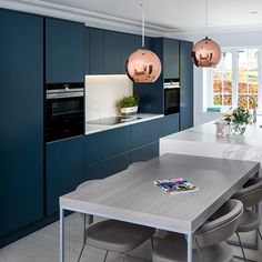 a modern kitchen with blue cabinets and white countertops is seen in this image from the dining room