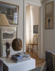 a living room filled with furniture and pictures on the wall next to a table topped with books