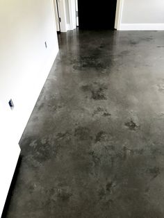 an empty room with white walls and black flooring is seen in this image from the front door