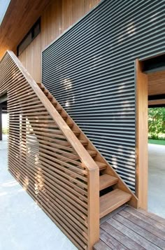 a wooden stair case next to a building with metal slats on the outside wall