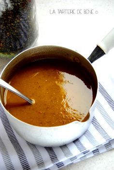 a bowl of soup with a spoon in it on a towel next to a jar of seasoning