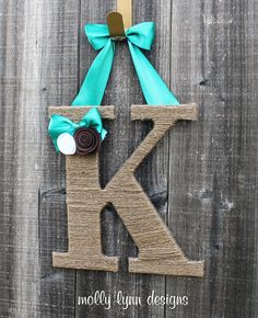 the letter k is made out of wood and has a green bow on it's front