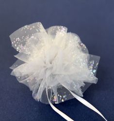 a white hair clip with sequins on it's side and a ribbon around the top