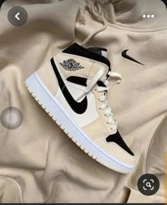 the nike air jordan 1 mid sneaker is on top of a beige sweatshirt with black and white accents