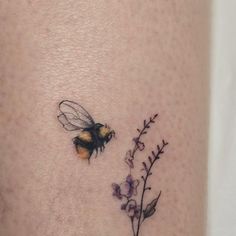 a small tattoo with a bee and flowers on it