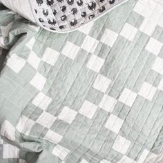 an unmade bed with a green and white checkered comforter