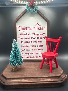 a small wooden chair sitting next to a sign with a christmas tree on top of it