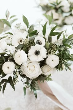 a bridal bouquet with white flowers and greenery