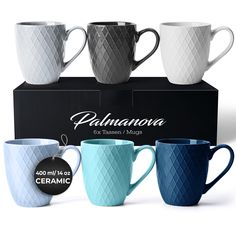 four different colored coffee mugs sitting next to each other in front of a black box