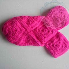 pink crocheted mittens on white surface with small object in the middle for decoration