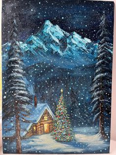 a painting of a cabin in the snow with a christmas tree and mountains behind it