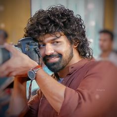 a man with curly hair holding a camera up to his face and taking a selfie