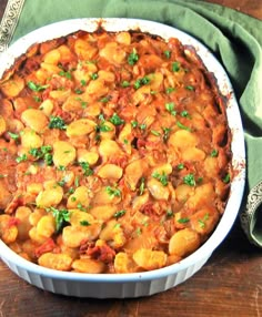 a casserole dish with chickpeas and tomato sauce on a wooden table