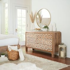 a room with a white rug and a wooden dresser in the corner, next to a mirror