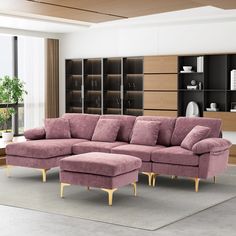 a living room with a large pink couch and matching footstool in front of a bookcase