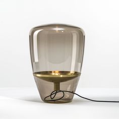 a table lamp with a cord plugged in to the side and a glass container on top