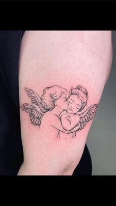 a woman with a small tattoo on her arm holding a baby in her arms and wings