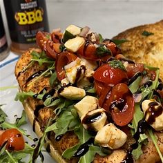 a white plate topped with chicken and veggies covered in sauce next to bread