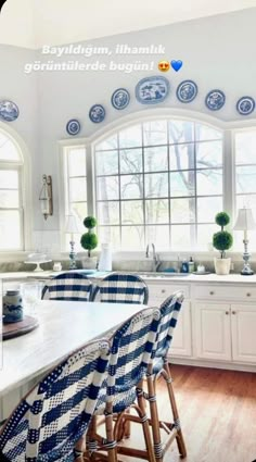 a kitchen with blue and white plates on the wall above the counter top, along with four bar stools