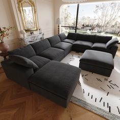 a large sectional couch sitting on top of a wooden floor next to a window in a living room