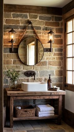 a bathroom with stone walls and a wooden vanity topped with a white sink under a round mirror