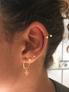 a close up of a person wearing gold ear piercings with small beads on them