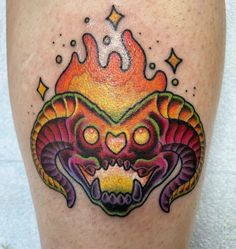 a colorful tattoo on the leg of a man with an evil face and flames coming out of his head