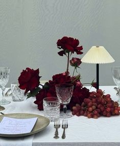 the table is set with red roses and wine glasses