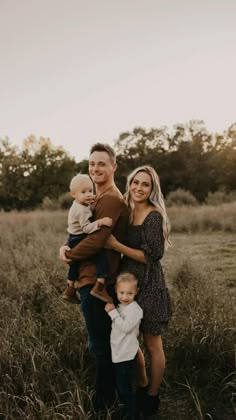 a family posing for a photo in the middle of a field with tall grass and trees