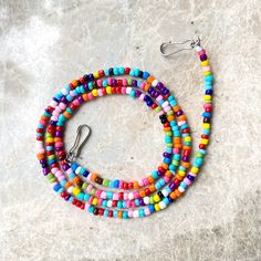 multicolored beaded bracelets with silver hooks on marble surface, top view