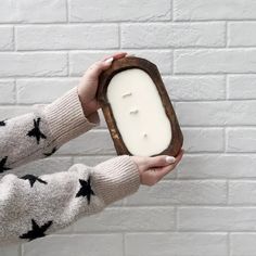 a person holding a candle in front of a white brick wall with black stars on it