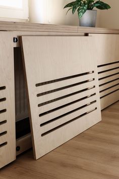 an open cabinet door on the floor with a potted plant next to it,