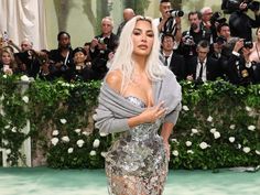 lady with white hair and silver dress standing in front of photographers